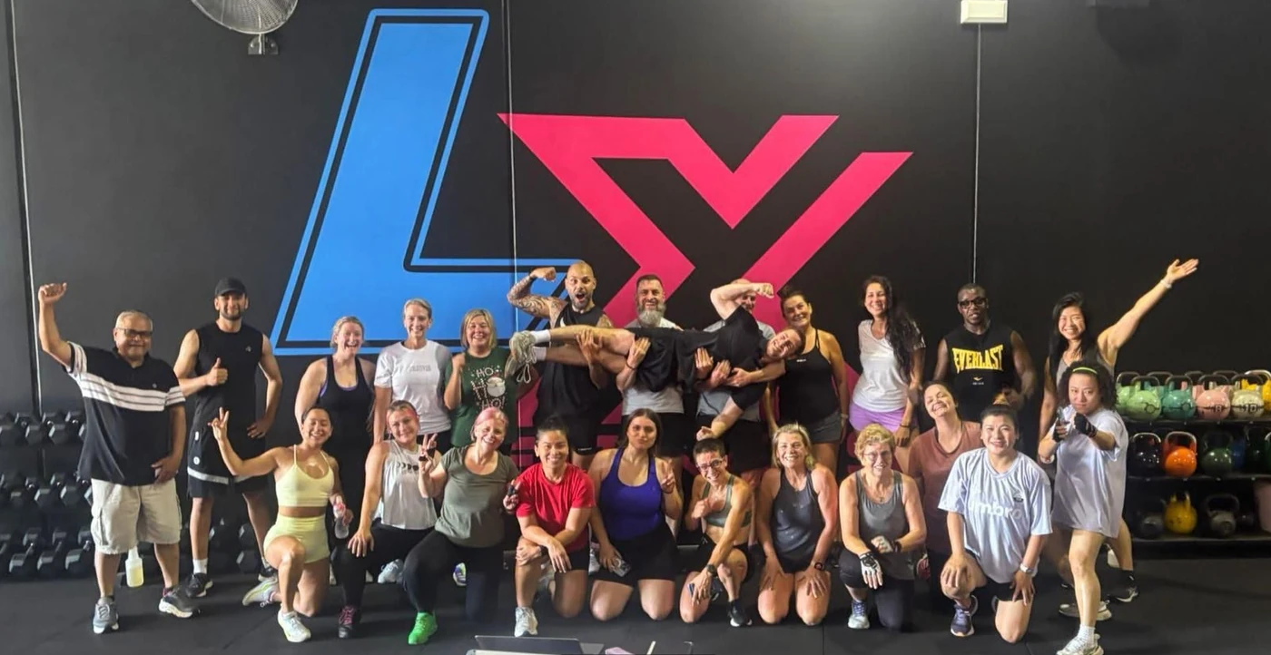 LX Fitness members and coaches together in front of the gym logo